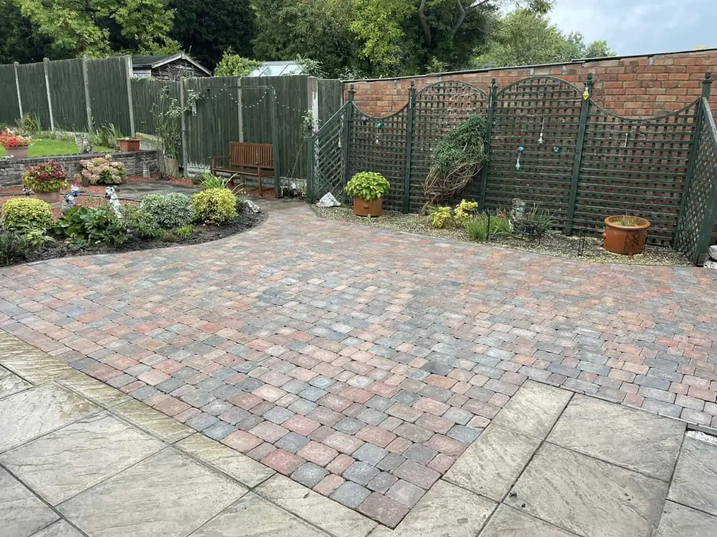 Multi-coloured block paving laid as a garden patio with defined planting beds.