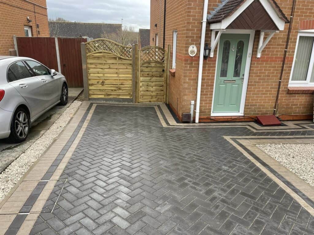 Charcoal herringbone block paving with contrasting border courses.