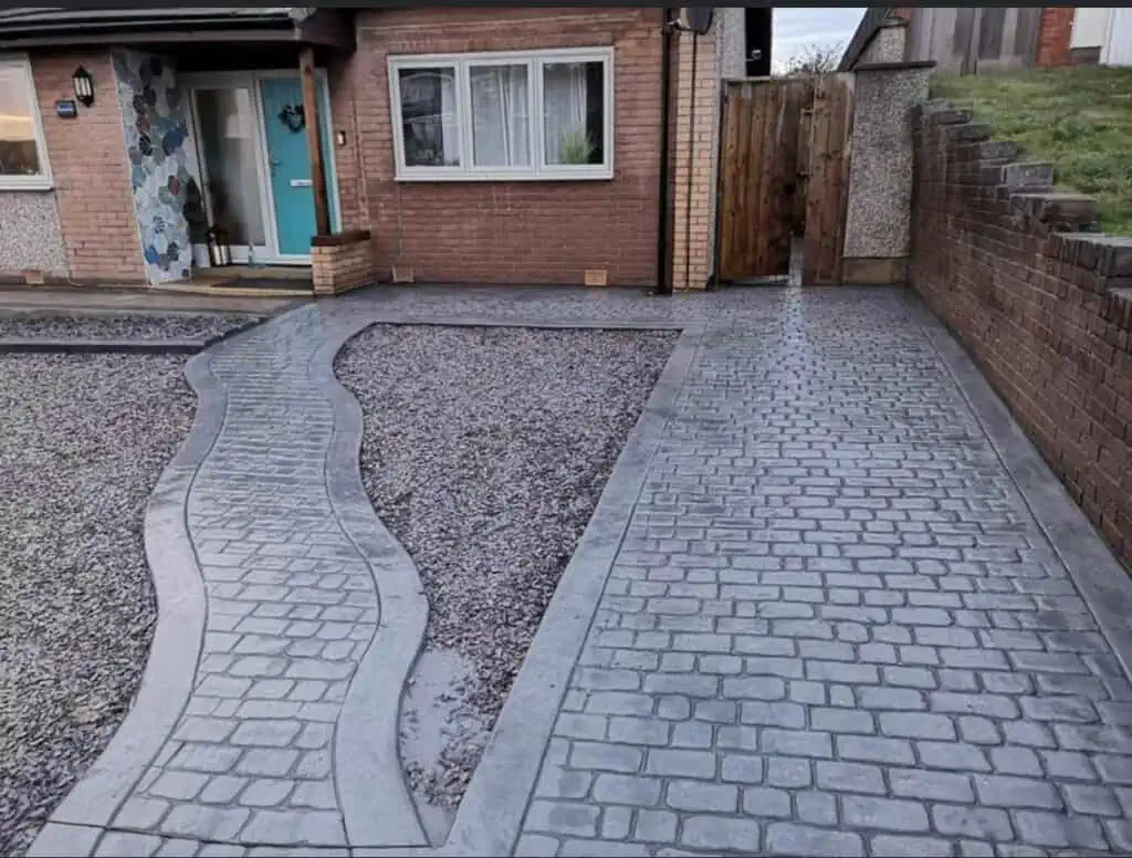 Grey imprinted concrete driveway with a patterned slab effect and defined joints.