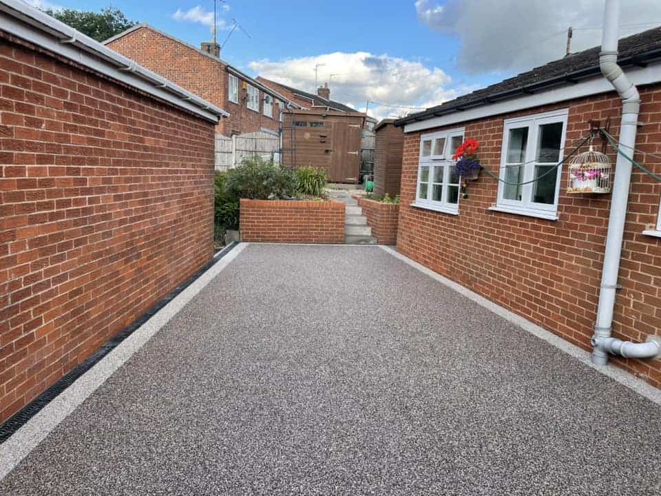 Heather resin-bound driveway Heather resin-bound driveway installed between brick walls with neat edge detailing.