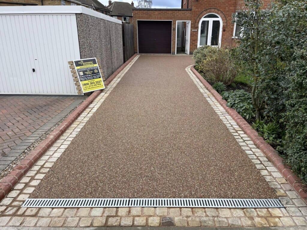 Rose resin-bound driveway Rose-coloured resin-bound driveway with contrasting block-paved borders and drainage.