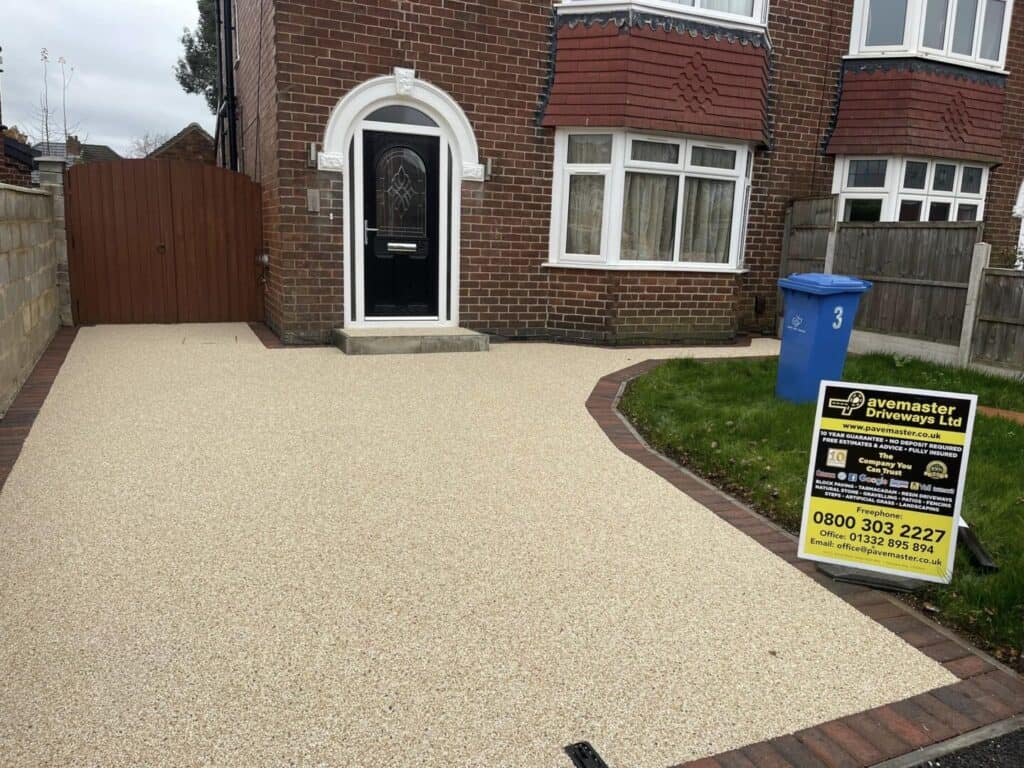 Light resin-bound driveway with a decorative aggregate finish and brick edging.