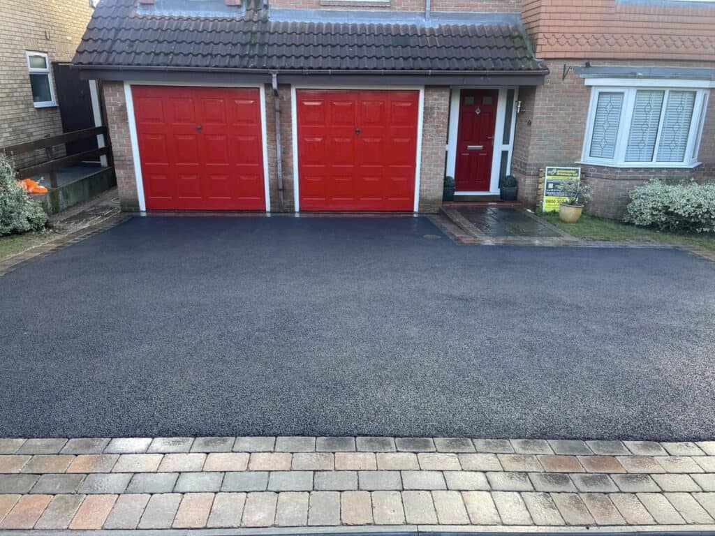 Fresh dark tarmac driveway finished with a defined paved perimeter.