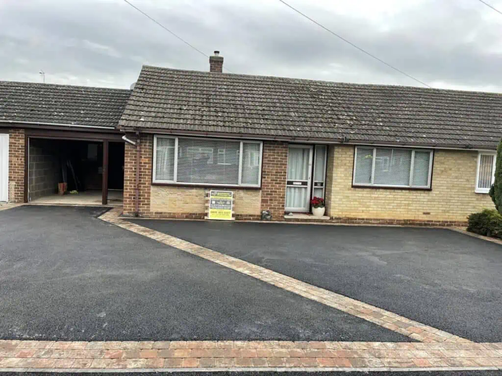 Large tarmac driveway Wide tarmac driveway with a neat block-paved border outside a bungalow.